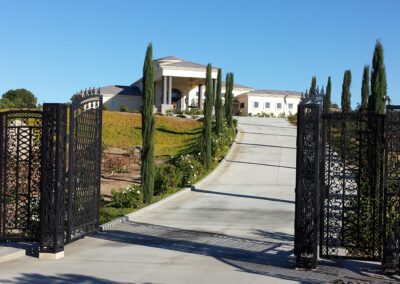 A driveway leading to a house with an iron gate.