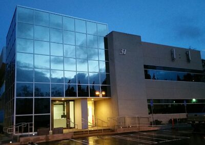 An office building at night with a car parked in front of it.