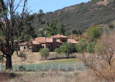 A house with a fence in the middle of a field.